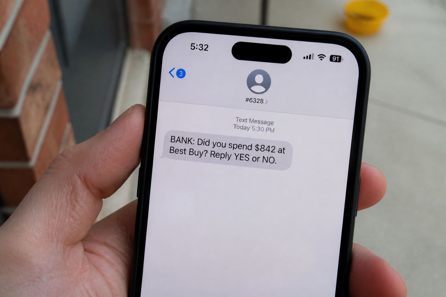 A phone showing a bank text that says reply YES or NO.