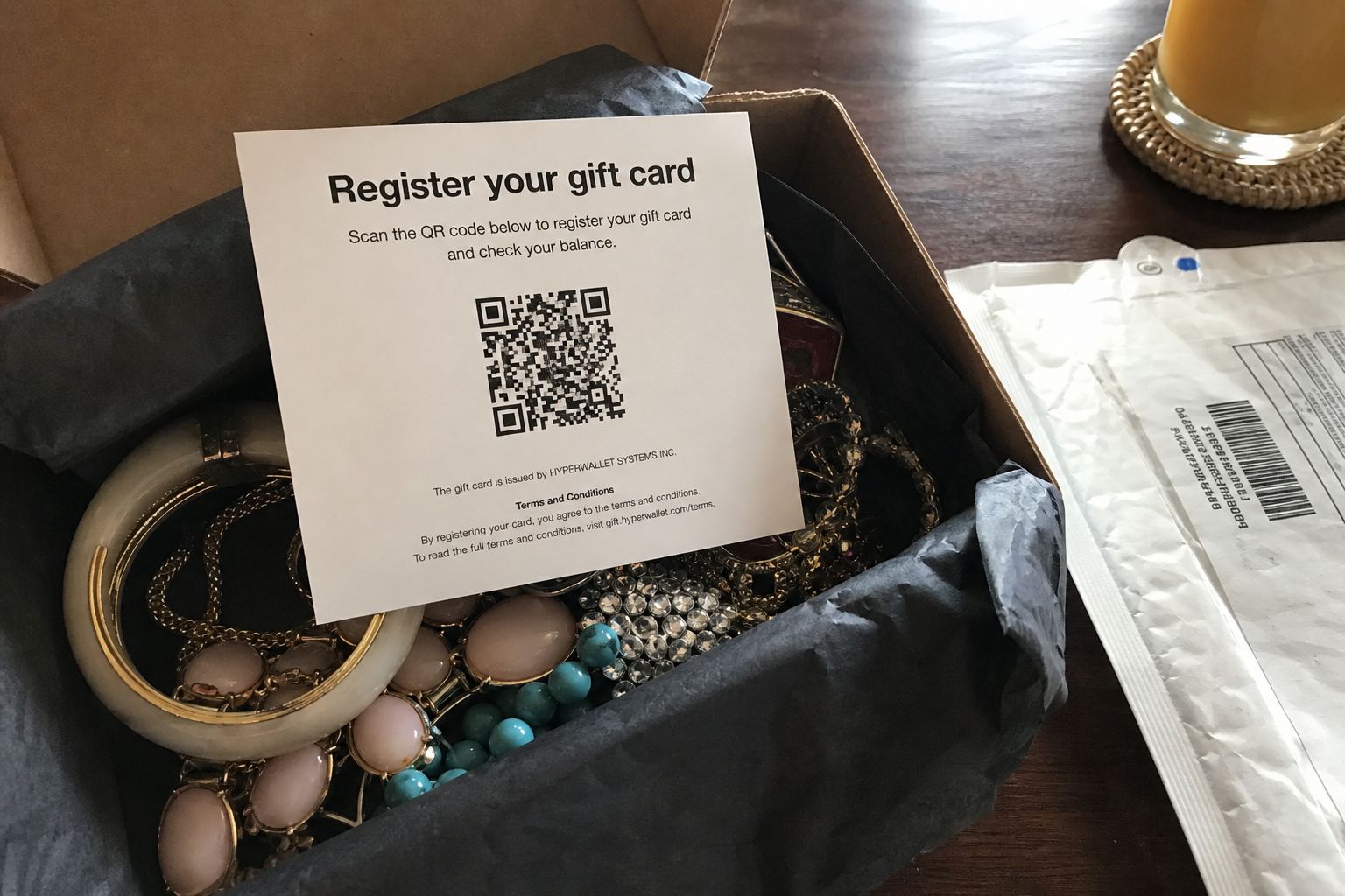 A register-your-gift-card insert sitting on cheap jewelry from an unordered box.