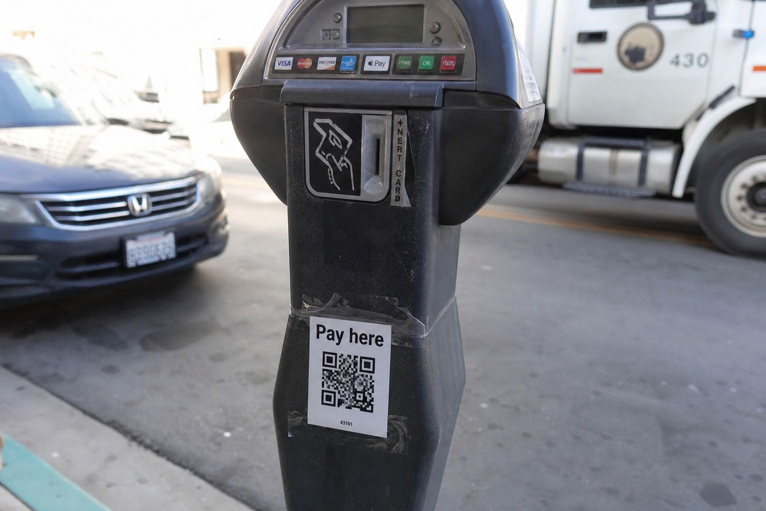 A parking meter with a freshly taped QR sticker.