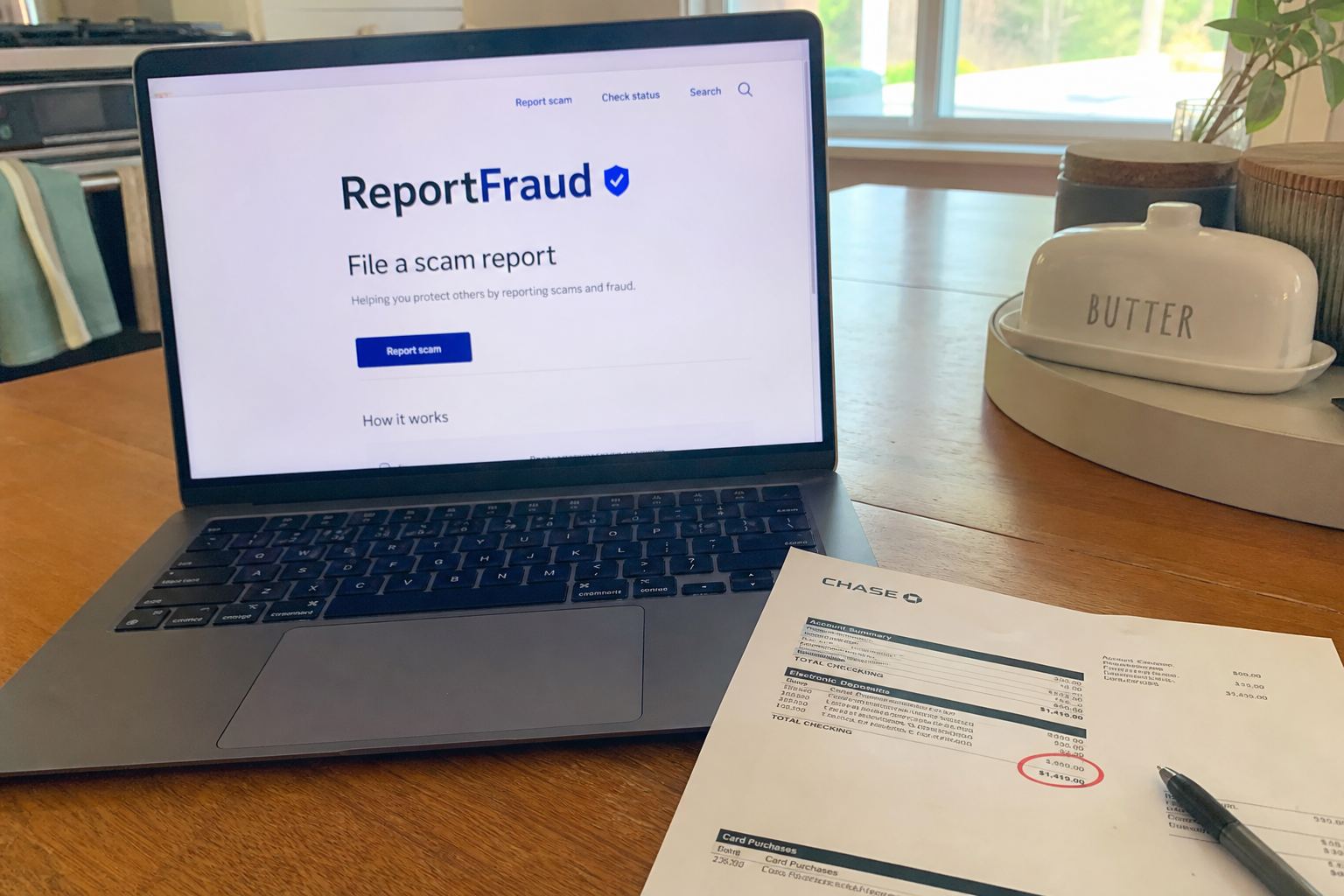 A laptop open to a scam-report page next to a bank statement.
