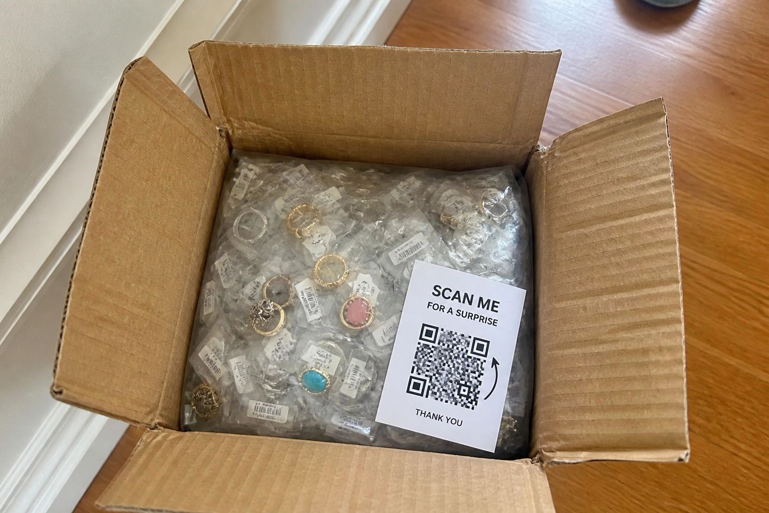 Cheap rings still in a plastic bag inside an open shipping box.